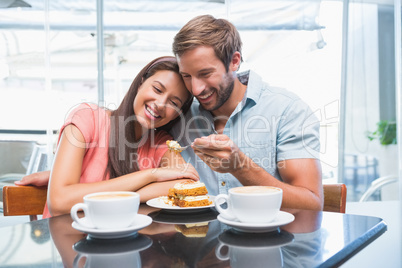 Young happy couple eating cake together