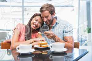 Young happy couple eating cake together