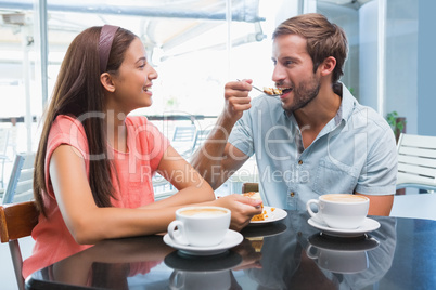 Young happy couple eating cake together