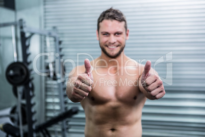 Portrait of smiling muscular man looking at camera with thumb up
