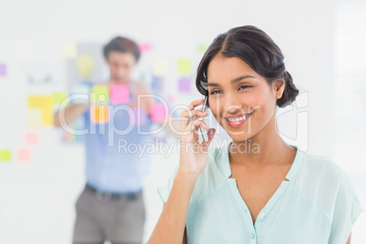 Businesswoman having phone call while her colleague posing