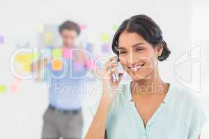 Businesswoman having phone call while her colleague posing