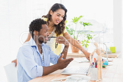 Young smiling businesswoman pointing at something on the laptop