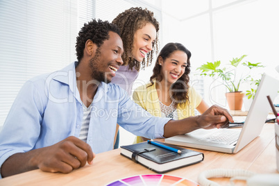 Happy coworkers using laptop and pointing the screen