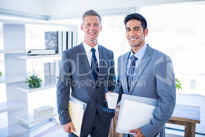 Happy businessman looking at camera and holding files
