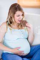 Pretty pregnant woman eating big bar of chocolate