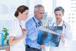 Concentrated medical colleagues examining x-ray together