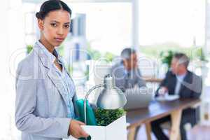 Businesswoman holding box and looking at camera