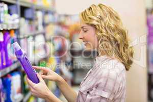 Side view of smiling pretty blonde woman looking at a product