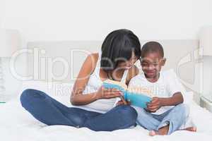 Pretty mother reading with his son in bed