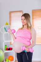 A pregnant woman holding dumbbells