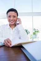 Businesswoman having phone call and looking at documents