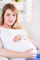 Pregnant woman looking at camera on the couch