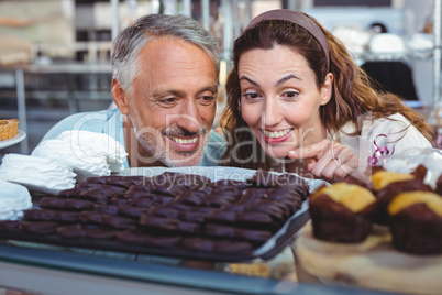 Happy couple pointing cakes
