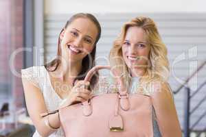 Happy women smiling at camera and holding a handbag