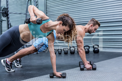 Muscular couple doing plank exercise together