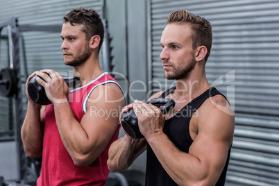 Muscular men exercising with kettlebells