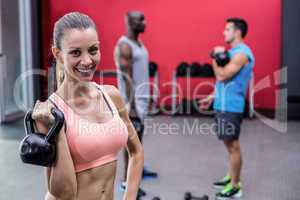Smiling muscular woman lifting a kettle bell