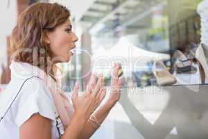 Astonished woman touching window with one hand