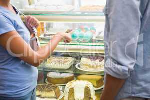 Young happy couple choosing cake