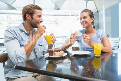 Young happy couple eating cake together