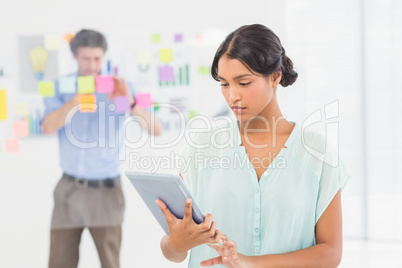 Creative businesswoman using tablet with colleague behind her