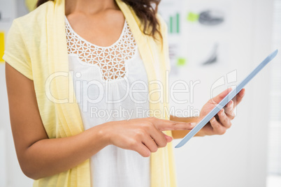 Young businesswoman holding and pointing at the tablet