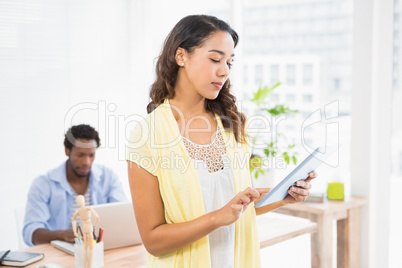 Woman posing in front of her colleague with tablet computer