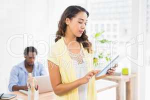 Woman posing in front of her colleague with tablet computer