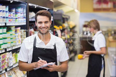 Portrait of smiling staff man writing on notepad