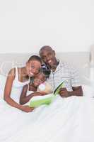 Portrait of a pretty couple reading a book with their daughter i