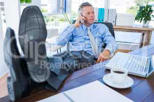 Businessman relaxing in a swivel chair and having a phone call