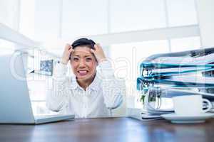 Businesswoman getting stressed at her desk