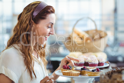 Astonished pretty woman pointing at cakes