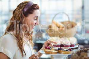 Astonished pretty woman pointing at cakes