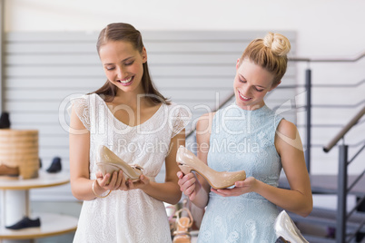 Two happy women holding heel shoes