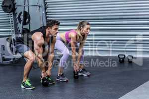 A muscular couple lifting kettlebells