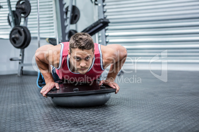 Portrait of muscular man using bosu ball