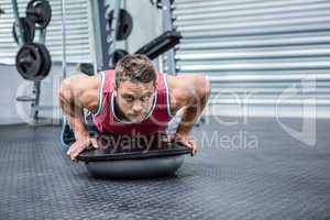 Portrait of muscular man using bosu ball