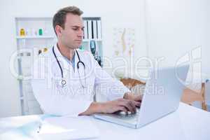 Focused doctor working with laptop