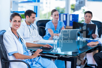 Happy doctor looking at camera with colleagues behind