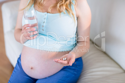 Pregnant woman taking a vitamin tablet