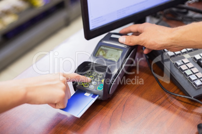 Woman paying with her credit card and doing his pin code