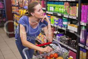 Thoughtful pretty brunette pushing trolley