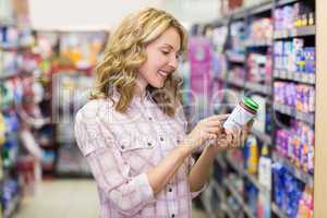 Side view of smiling pretty blonde woman looking at a product