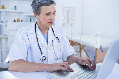 Serious female doctor using her laptop computer