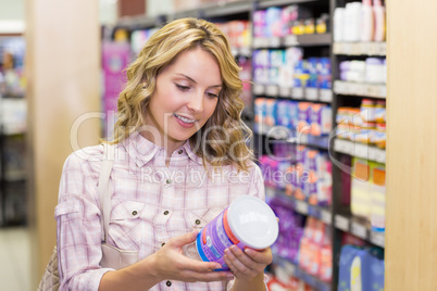 Smiling pretty blonde woman looking at a product