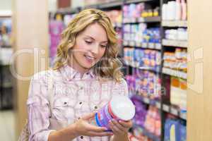 Smiling pretty blonde woman looking at a product