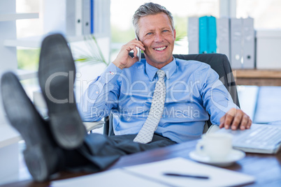 Businessman relaxing in a swivel chair and having a phone call