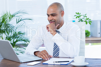 Smiling businessman looking at his laptop